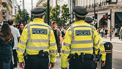 Two Met Police Officers walking along a pavement