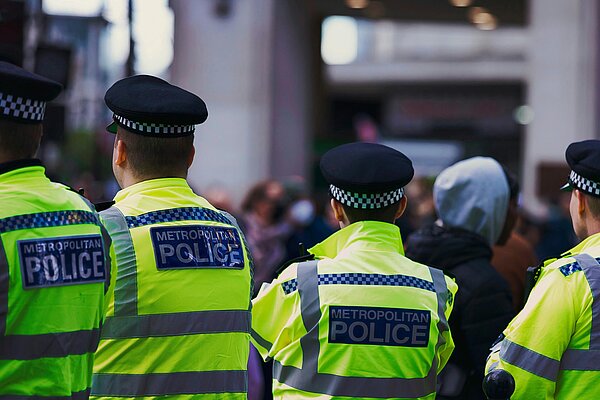 A photo of several Metropolitan Police Officers in fluorescent jackets from behind.
