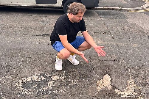Liberal Democrat campaigner Alex Lewis showing the damage to the road