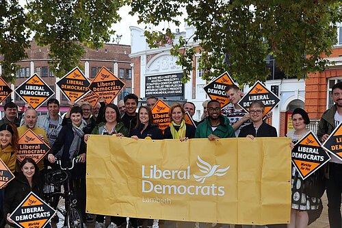 Assembled people holding Lib Dem signs